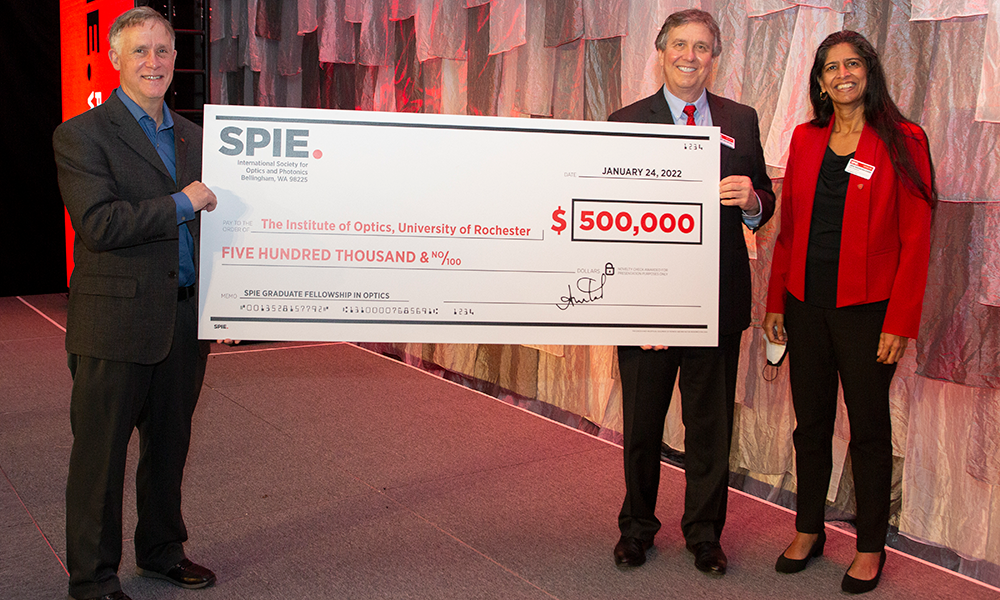 An image of three people holding an oversize check for $500,000, for the University of Rochester