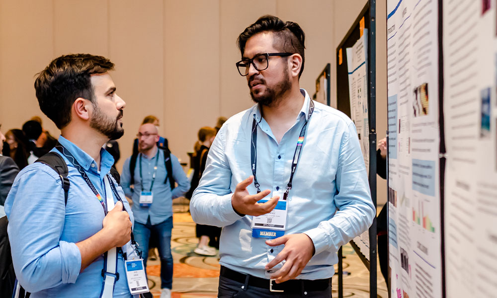 Two men talking about a scientific poster at a conference