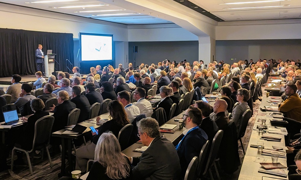 Room full of people looking at a speaker on stage