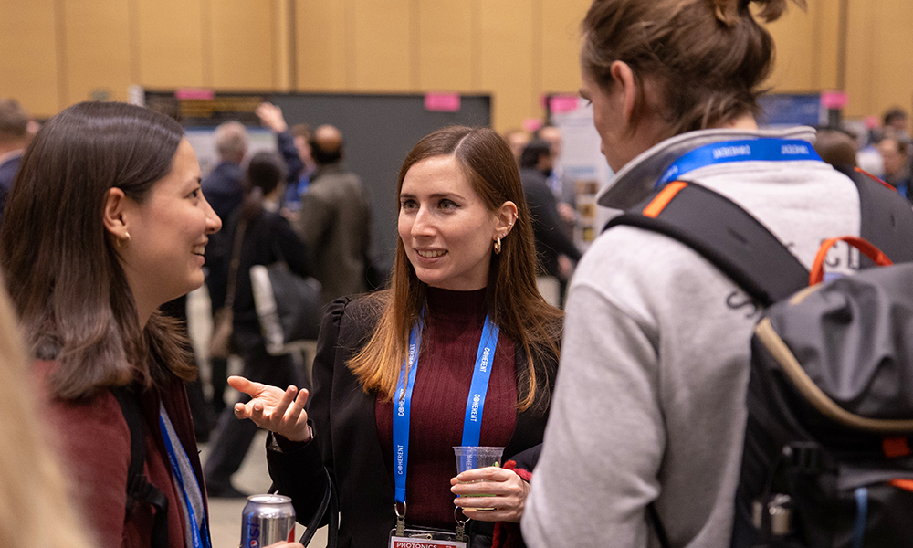 Two females and a male stand together networking at SPIE Photonics West