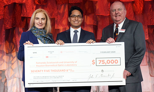 Recipient holding a giant check while receiving the Hillenkamp Fellowship